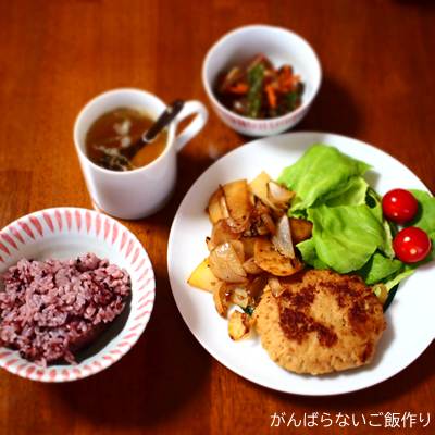 豆腐ハンバーグに炒め野菜と生野菜サラダが添えられた献立。黒米入りご飯、たまねぎスープ、つきこんにゃく煮の組み合わせ。