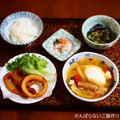 卵入りウインナー・キャベツ・ミニトマトのスープ煮の献立。白ご飯、オニオンリングフライ、ナスの揚げびたし、ニシン菜の花の組み合わせ。