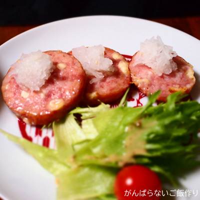 焼いたチーズリオナソーセージに大根おろしをトッピングした一皿。フリルレタスとミニトマトが添えられている。