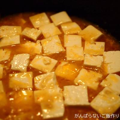 調理中の丸美屋 黄金の麻婆豆腐。フライパンに調味ソースと豆腐を煮立たせた状態。